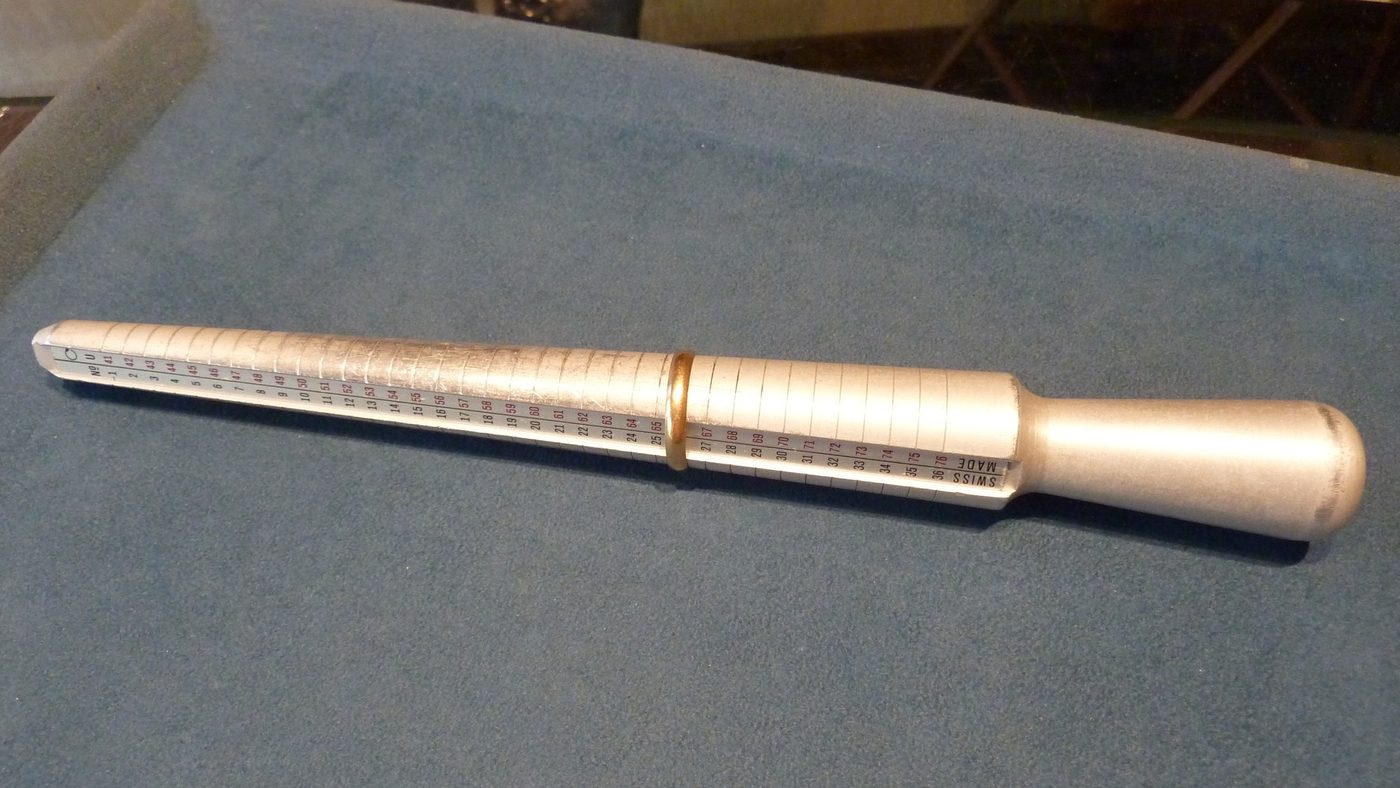 A graduated steel ring mandrel resting on a blue cloth in a workshop