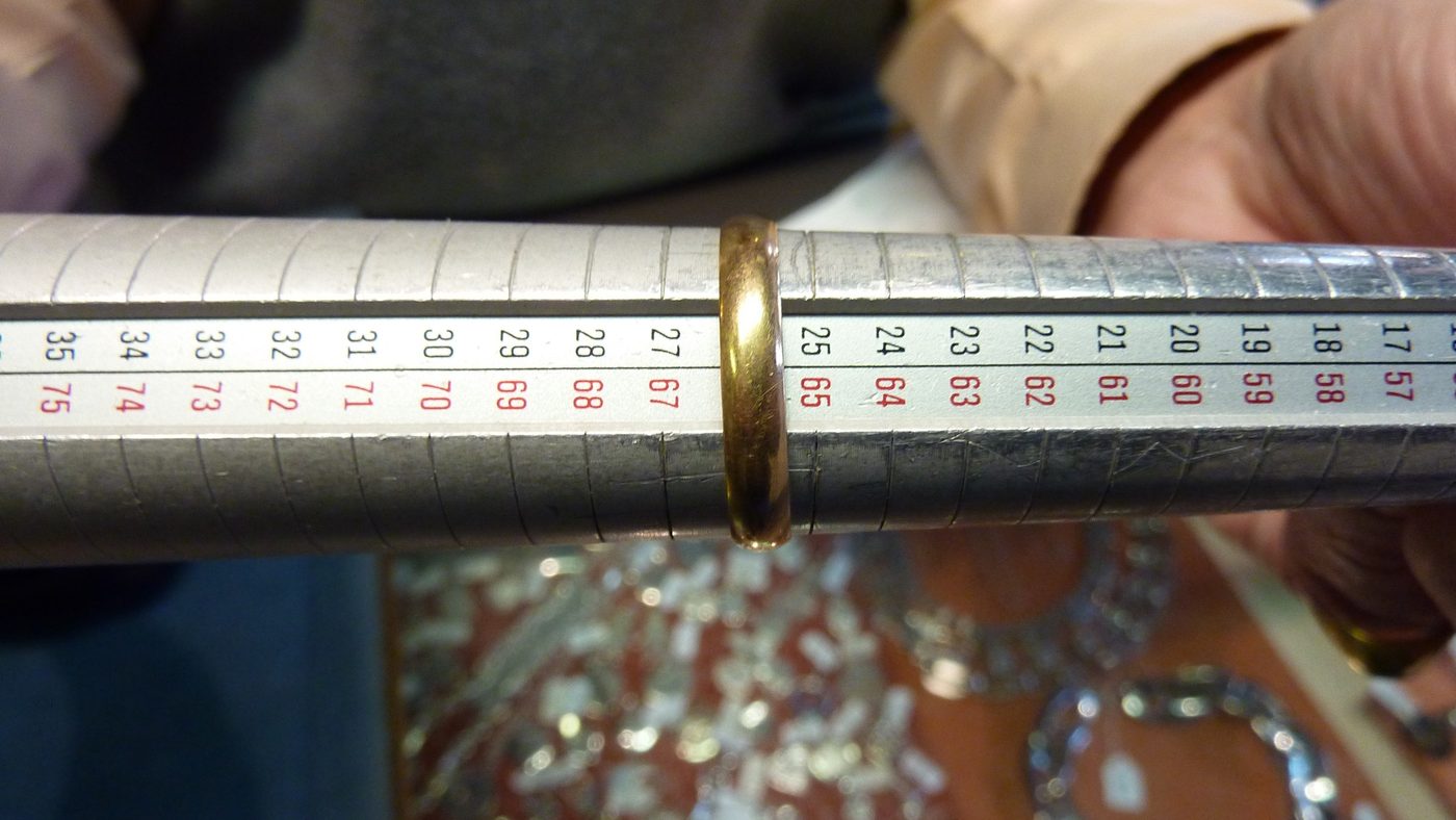 A gold ring being measured against the graduated scale of a steel ring mandrel